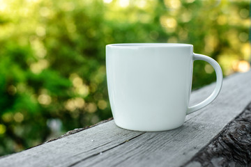 White coffee cup on wooden desk outdoors