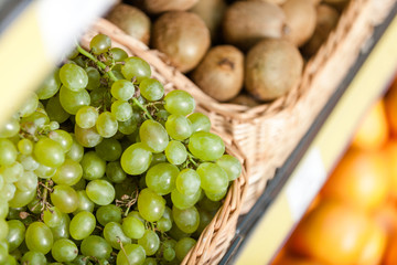 Close up view of grape and fresh kiwis in the braided basket 