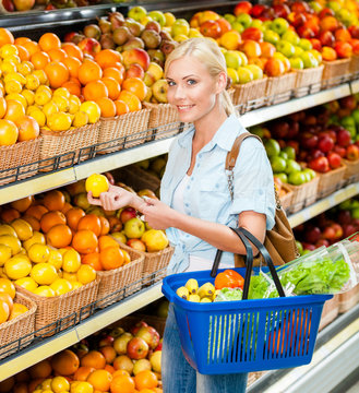 Girl at the shop choosing fruits and vegetables hands lemon