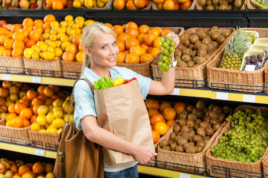 Choosing grape girl hands bag with fresh vegetables