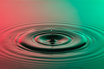 Water drop close up with concentric ripples colourful red and gr