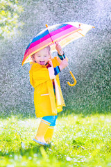 Funny toddler with umbrella playing in the rain