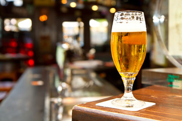 Glass of light beer on a dark pub