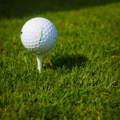 Golf ball on a tee against the golf course with copy space