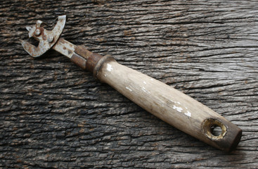 Old dirty, rusty can opener with wood handle