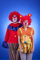 Clown couple in costumes on blue background
