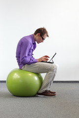 man with tablet on large stability  ball - bad sitting posture