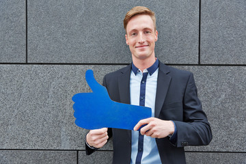 Mann hält großen blauen Daumen hoch