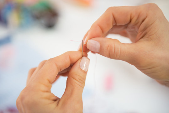 Closeup on seamstress threading needle