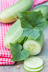 Green cucumbers and slices on a wooden background