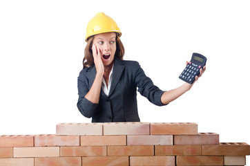 Woman construction worker with calculator on white
