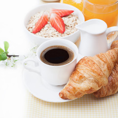 Coffee cup, croissant, oatmeal with strawberries, fruit juice, o