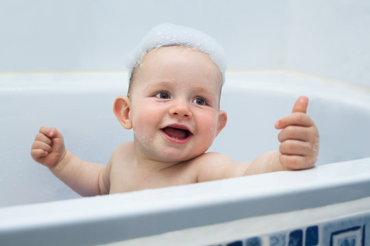 Happy baby boy in bath showing thumb up