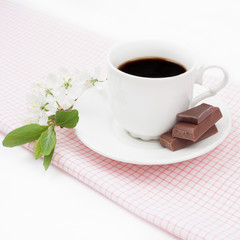 Coffee cup with chocolate and a sprig of cherry blossoms