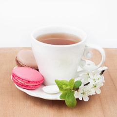 Cup of tea and sweet and colourful french macaroon and a cherry