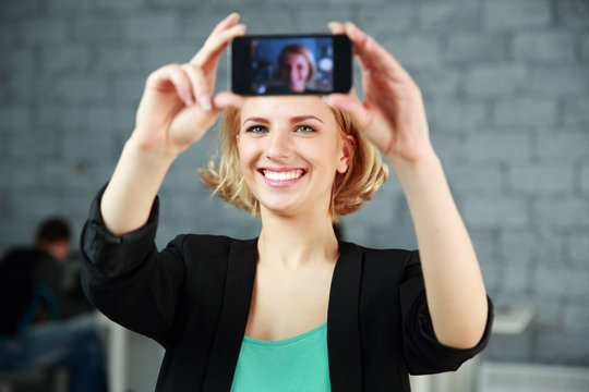 woman making a self photo by her smartphone in office
