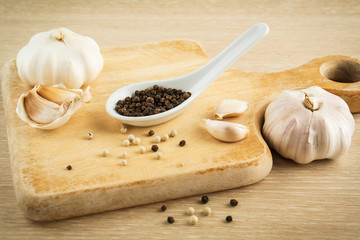 Black peppercorns on spoon and garlic