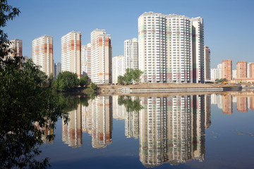 Obraz premium Many block of flats over river and clear blue sky