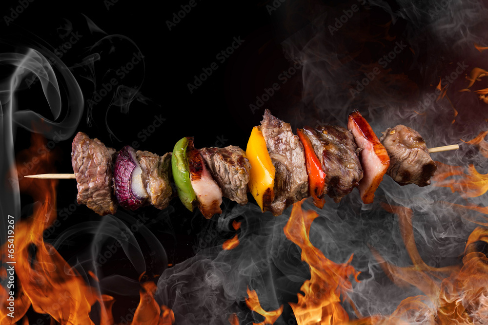 Wall mural Tasty skewers with fire flames.