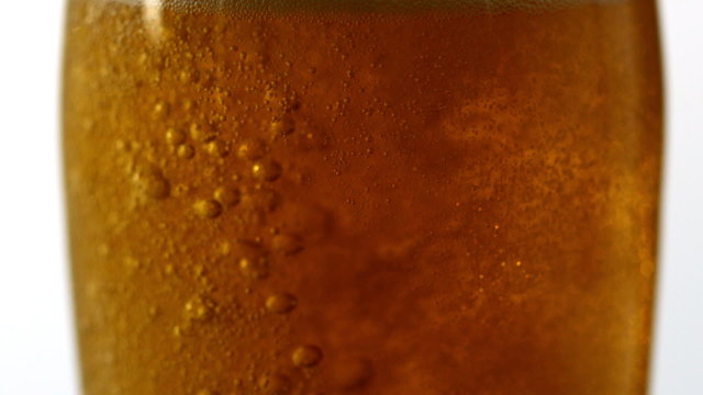 Glass of beer bubbling on white background