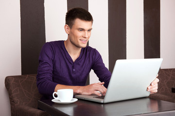 young man sitting in cafe and working.