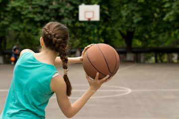 Young slender teenage girl playing basketball