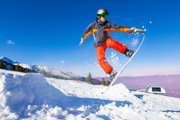 Naklejka na ściany i meble Snowboarder holding board during jump