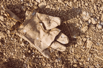 Old construction glove on the ground. Retro filter.