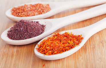 East spices in wooden spoons, on a wooden background
