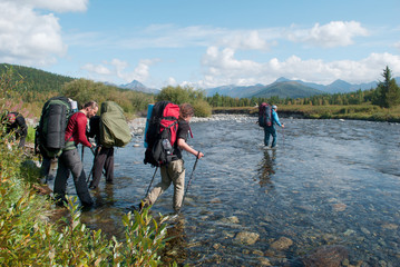 hikers crossing mountain river, Ural, Russia