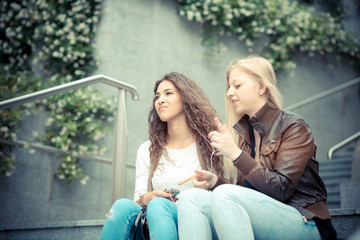 blonde and brunette beautiful stylish young women using smart ph