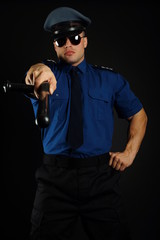 Policeman shows on you with nightstick on dark background