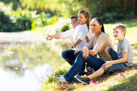 young family sitting by lake