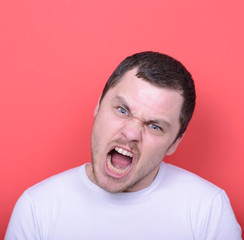 Portrait of angry man screaming against red background