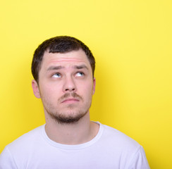 Portrait of happy young man looking up against yellow background