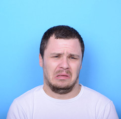 Fototapeta premium Portrait of man with dusgusted gesture against blue background