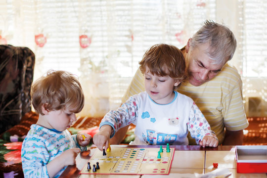 Two little sibling boys playing with grandfather board game
