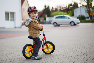 Fototapeta premium Little toddler boy learning to ride on his first bike