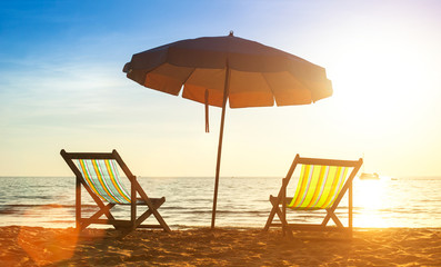Beach loungers on deserted coast sea at sunrise