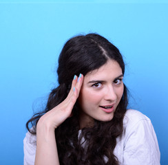 Fototapeta premium Portrait of girl with shock gesture looking up against blue back