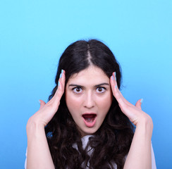 Portrait of girl with shock gesture looking up against blue back