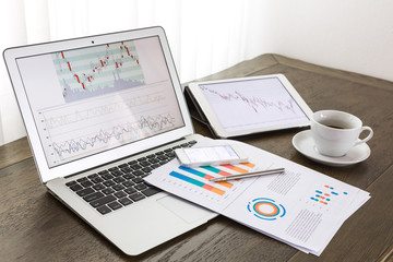 Laptop, tablet , smartphone and coffee cup with financial docume
