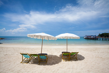 Beach chairs on the white sand beach with cloudy blue sky