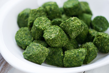 Close-up of a glass plate with spinach cubes, horizontal shot © Nickola_Che