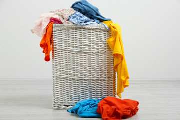 Full laundry basket  on wooden floor on gray background