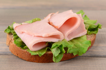 Delicious sandwich with lettuce and ham on table close-up
