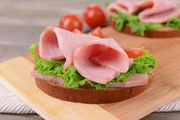 Delicious sandwiches with lettuce and ham on table close-up