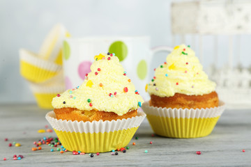 Tasty cup cakes with cream on grey wooden table