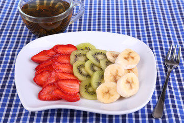 Various sliced fruits on plate on napkin close-up
