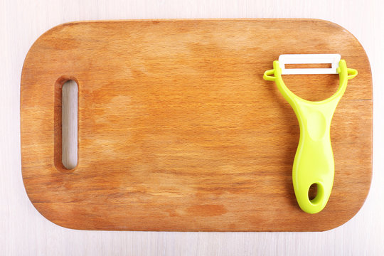 Vegetable peller and cutting board on wooden table